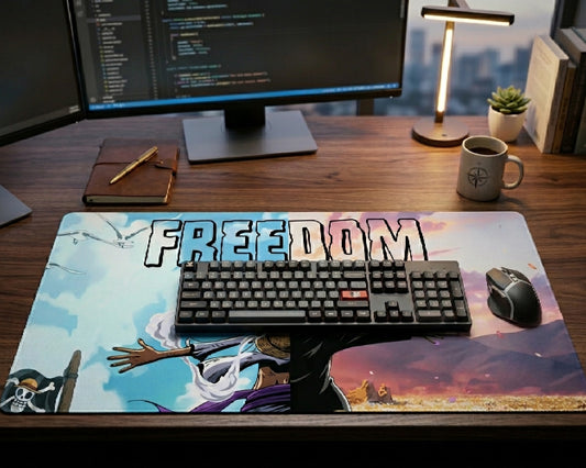 One Piece Freedom themed anime desk mat featuring Luffy and scenic sky artwork on a clean workstation desk with mechanical keyboard, monitor, and wireless mouse