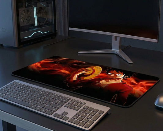 Gaming desk setup with keyboard, monitor, and anime-themed extended mouse pad featuring fiery character design.