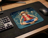Close-up view of One Piece Luffy gaming mouse pad with anime artwork beside RGB keyboard and wireless mouse