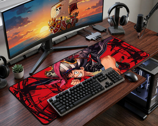 Gaming desk setup with extended One Piece Luffy mouse pad, ultrawide monitor displaying Thousand Sunny ship, mechanical keyboard, headphones, and RGB workspace.
