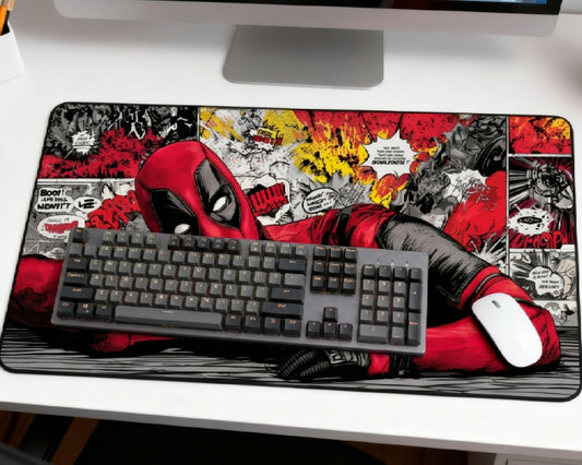 Deadpool comic desk mat setup with gray mechanical keyboard, white mouse, iMac, and red black comic panel artwork on a white desk.