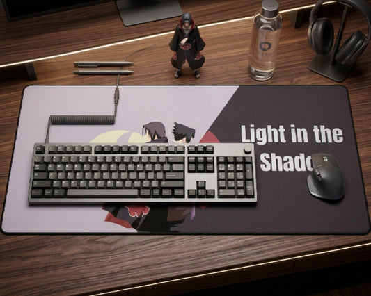 Itachi Uchiha Light in the Shadow desk mat with gray mechanical keyboard, mouse, figure, water bottle, pens, headphones, and warm desk lighting.