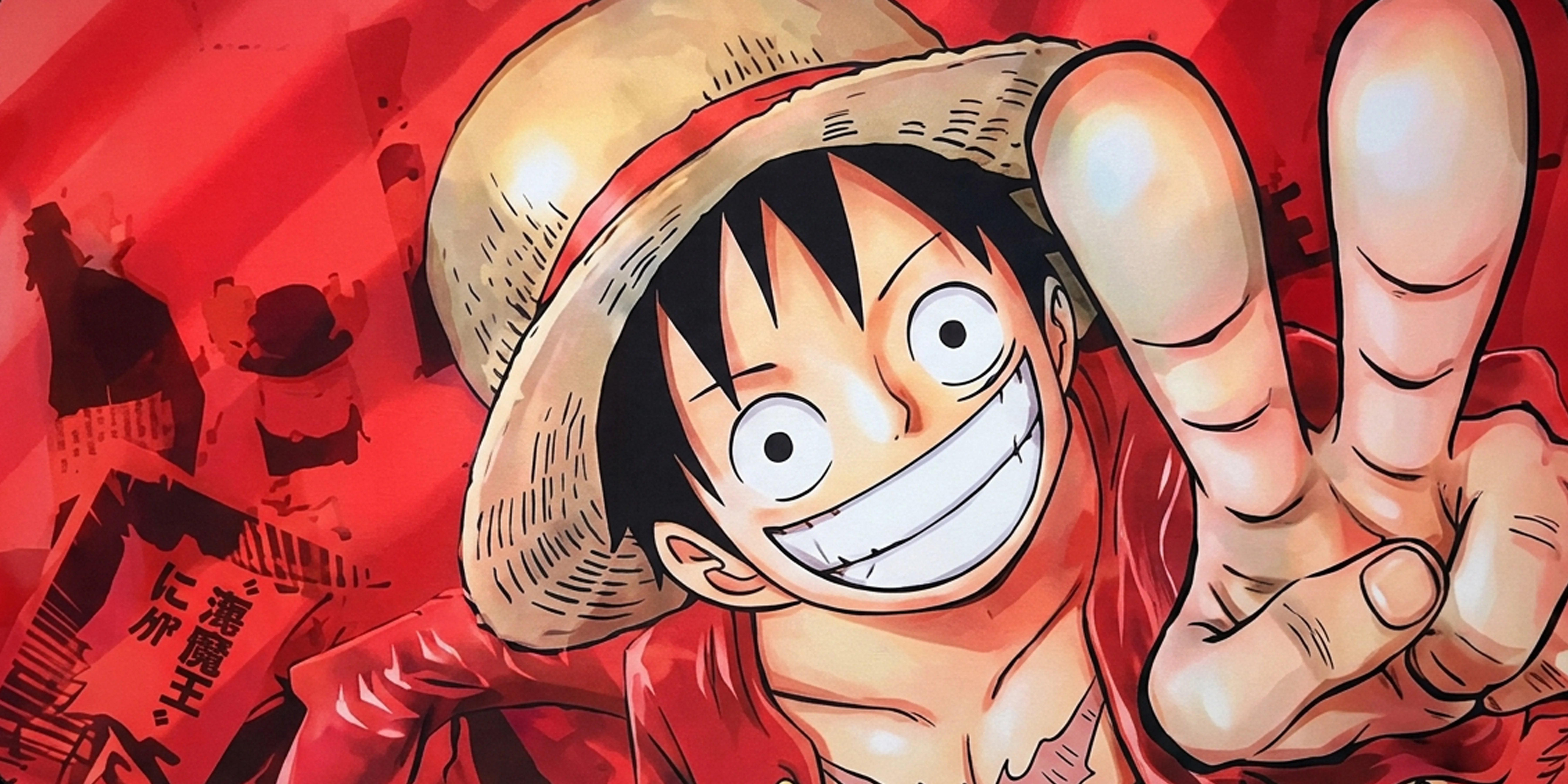 Close-up of Monkey D. Luffy from One Piece smiling and pointing, printed on vibrant red anime desk mat.