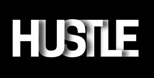 Close-up of bold ‘HUSTLE’ typography on black desk mat, minimalist motivational design for discipline and work ethic.