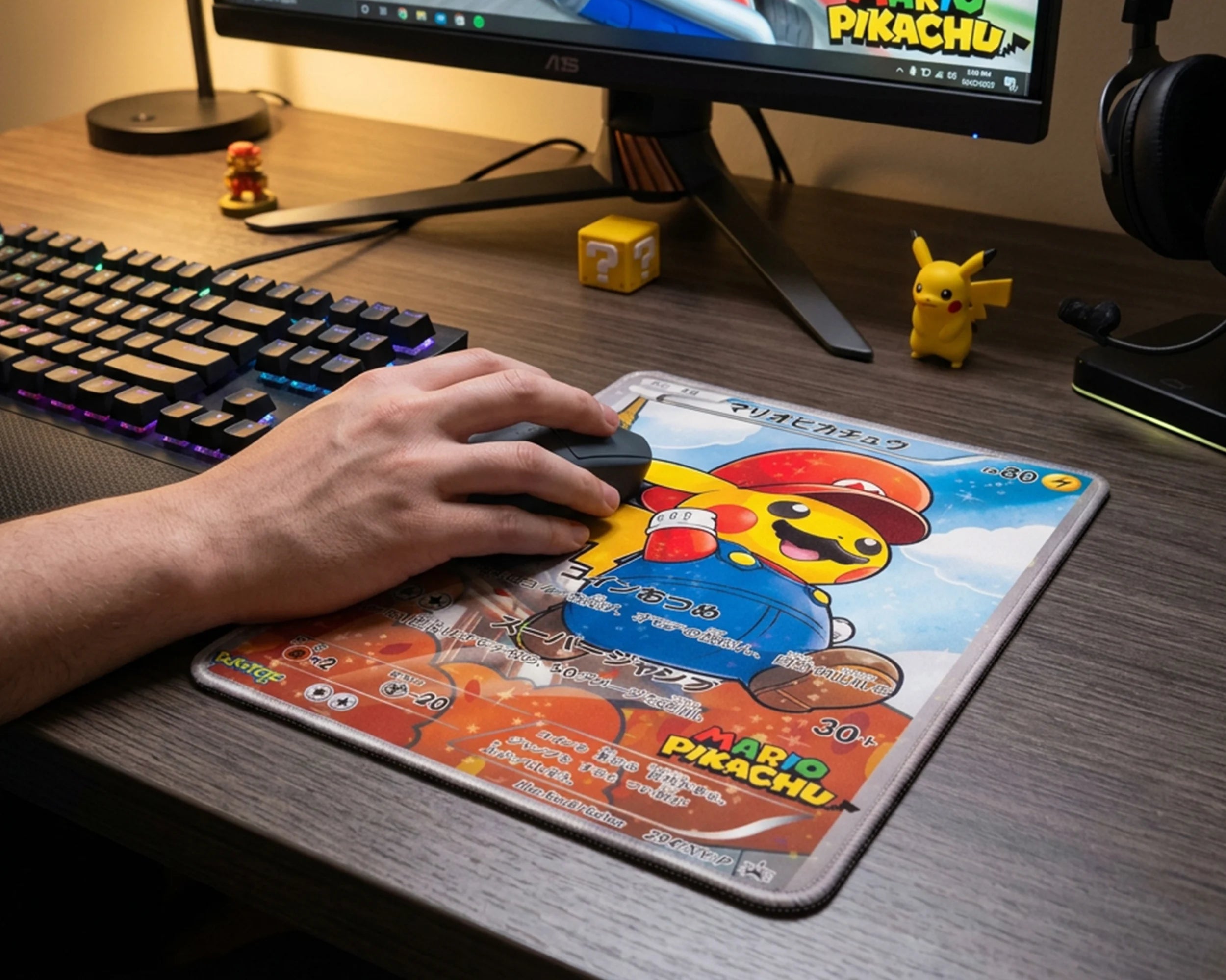Hand using Mario Pikachu Pokémon card mouse pad on RGB gaming desk setup with mechanical keyboard and monitor