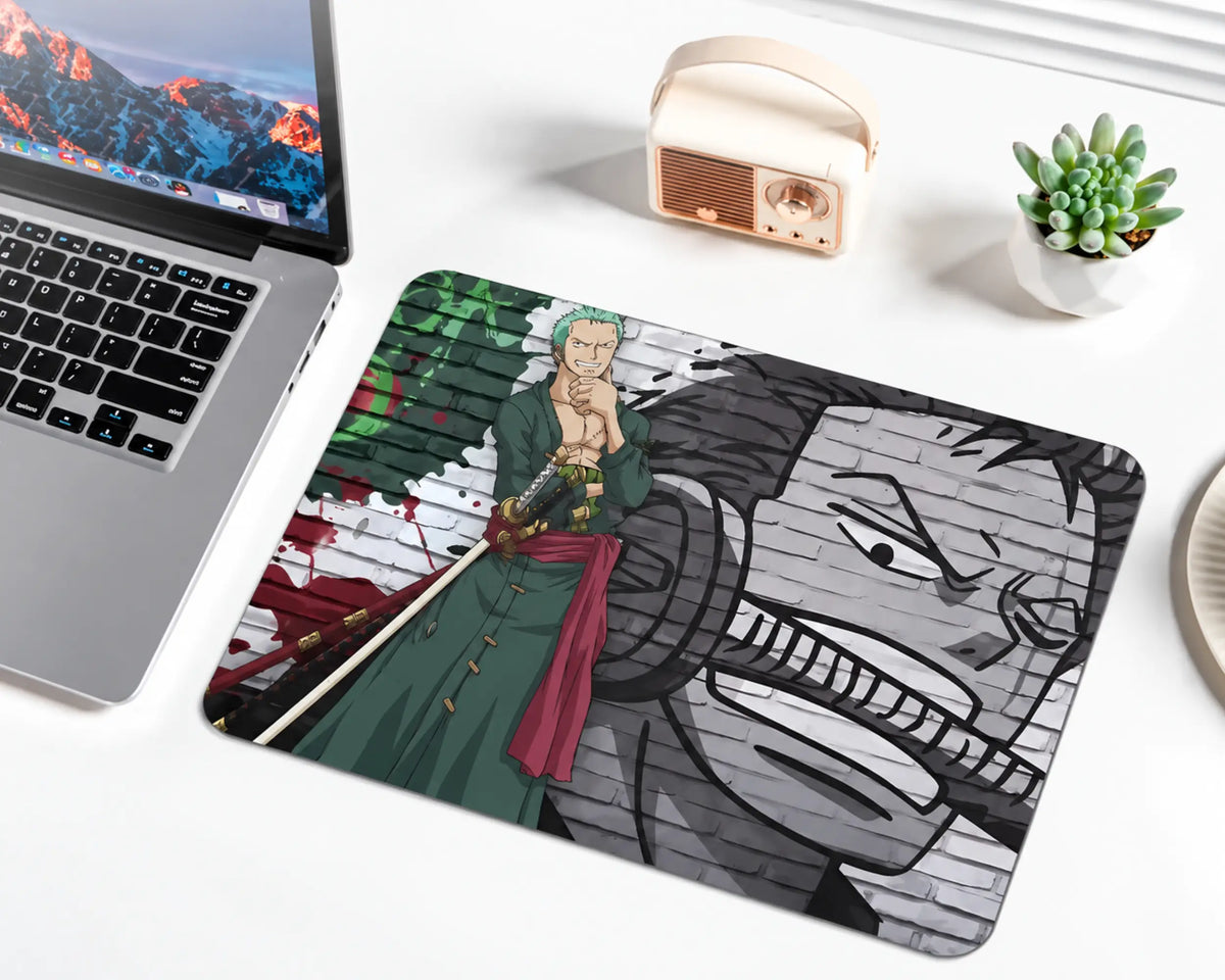 Roronoa Zoro from One Piece with short green hair, a dark green robe, red waist sash, and swords, standing against a green, red, black, and gray graffiti brick wall with a large monochrome portrait on a gaming mouse pad.