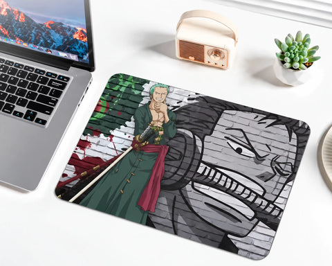 Roronoa Zoro from One Piece with short green hair, a dark green robe, red waist sash, and swords, standing against a green, red, black, and gray graffiti brick wall with a large monochrome portrait on a gaming mouse pad.