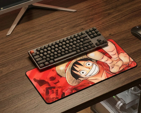 Gaming desk with extended One Piece Luffy mouse pad, mechanical keyboard, and clean wooden desktop setup.