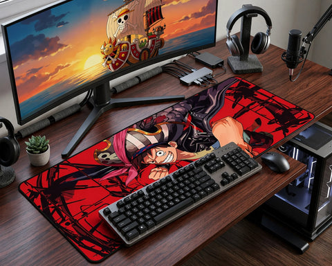 Gaming desk setup with extended One Piece Luffy mouse pad, ultrawide monitor displaying Thousand Sunny ship, mechanical keyboard, headphones, and RGB workspace.