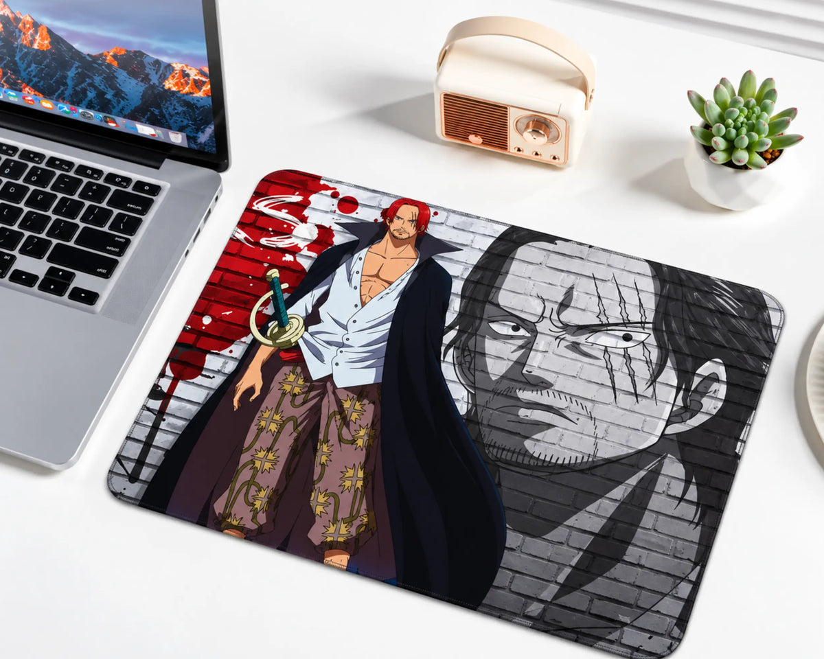Red-Haired Shanks from One Piece with red hair, facial scars, an open white shirt, patterned trousers, and a black cape, standing against a red and gray graffiti brick wall with a large monochrome portrait on a gaming mouse pad.