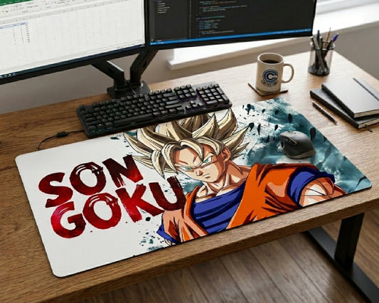 Dragon Ball Son Goku anime desk mat with bold red typography and Super Saiyan artwork placed on a wooden workstation desk with dual monitors and gaming accessories