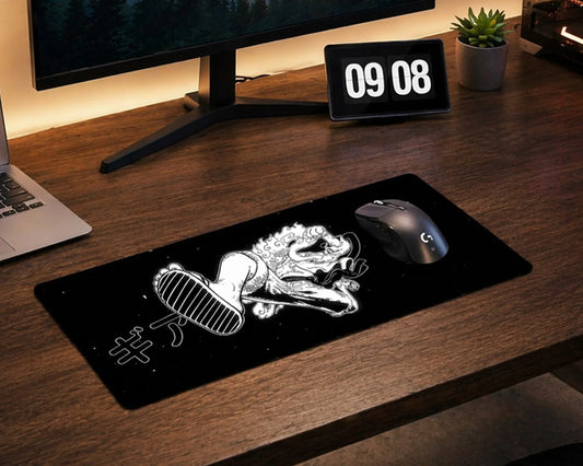 Minimalist gaming desk setup with black anime mouse pad featuring stylized Luffy artwork, mechanical keyboard, monitor, and clean wooden workspace.