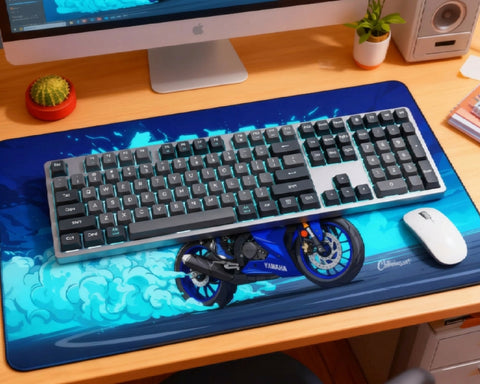 Blue Yamaha motorcycle desk mat setup with gray mechanical keyboard, teal backlighting, white mouse, iMac, cactus, plant, speaker, and wooden desk.