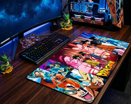 Dragon Ball Z gaming desk setup with large colorful anime desk mat, RGB keyboard, mouse, curved monitor, Dragon Ball collectibles, Shenron figures, and custom PC.