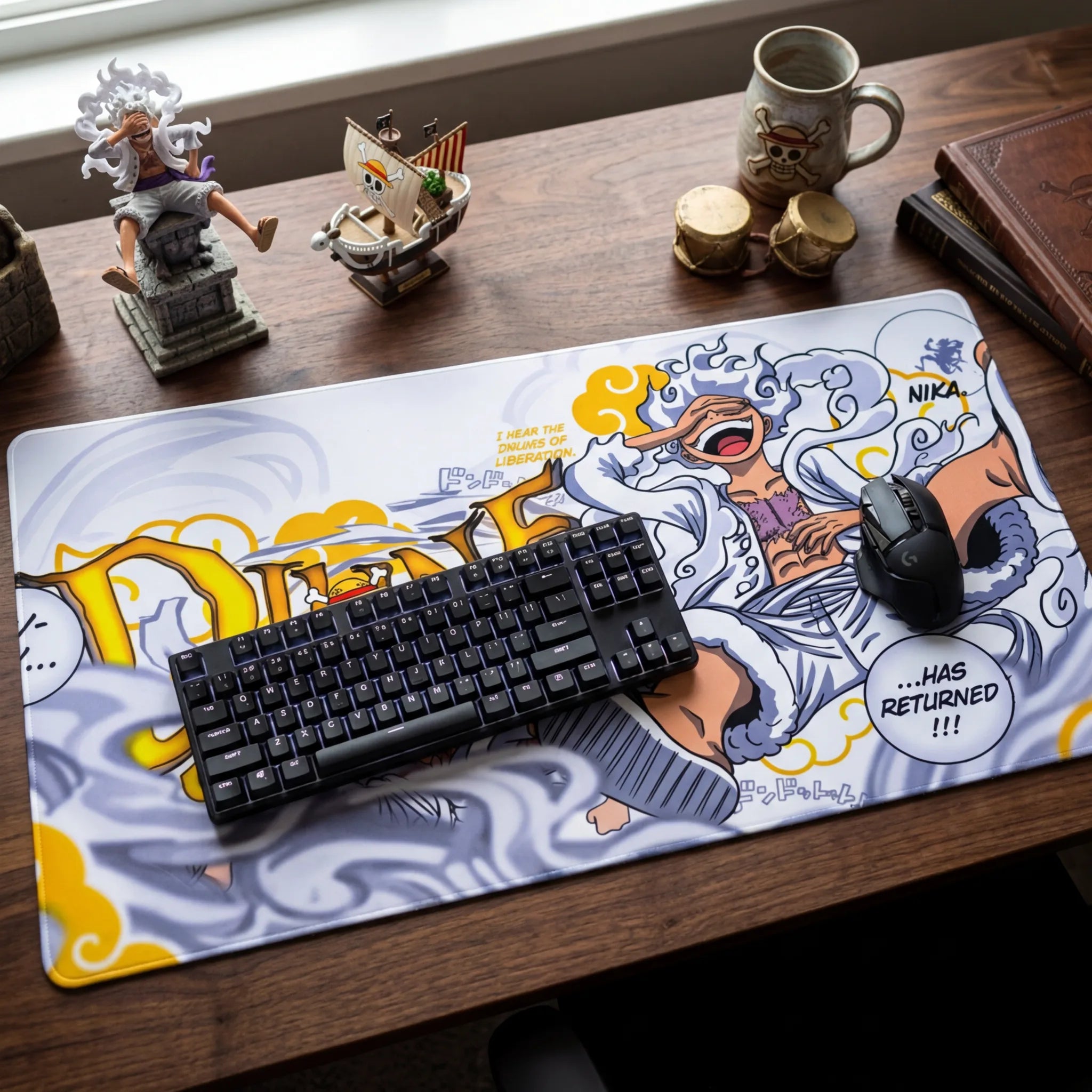 Anime desk setup featuring a large One Piece Gear 5 Luffy mouse pad with keyboard, mouse, and collectible figures on a wooden desk.